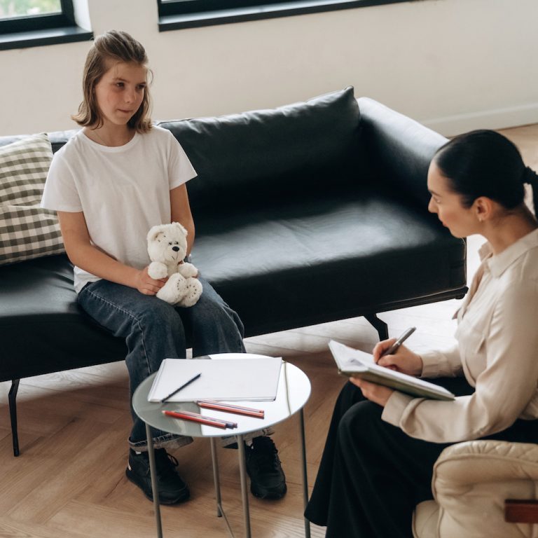 Holding toy bear. Girl at a psychologist's appointment.