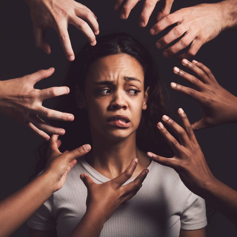 Shot of hands grabbing a young womans against a dark background.