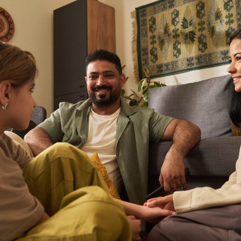 Happy family enjoying quality time in warm living room, smiling and interacting with each other on comfortable couch in cozy environment preparing for evening activities