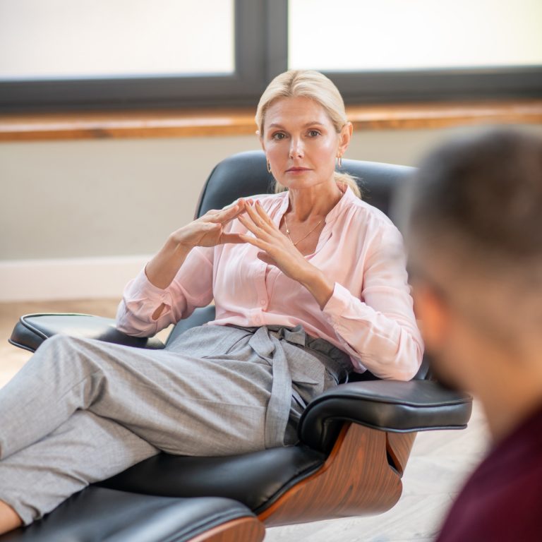 Sitting and speaking. Beautiful blonde-haired woman sitting and speaking with psychoanalyst