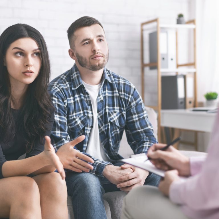 Family disagreement. Young couple discussing their problems at marital therapy with psychologist