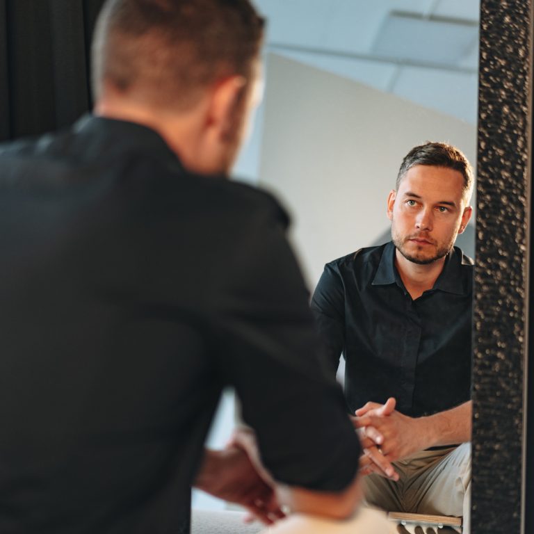 Young man looking at himself in the mirror indoors